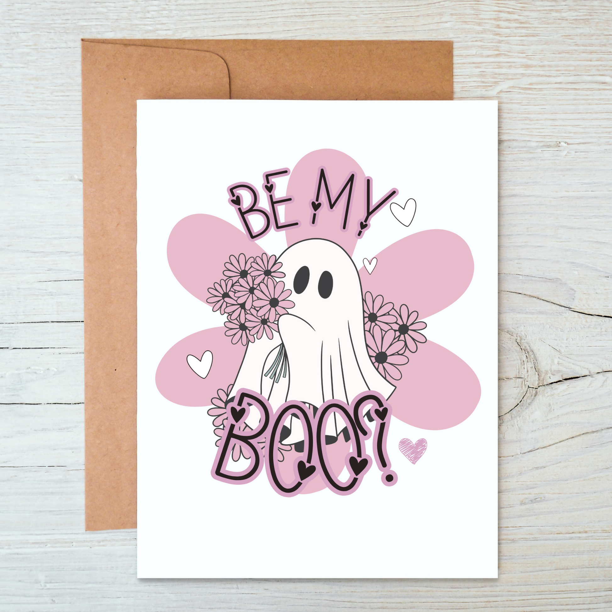 White greeting card with brown envelope. The card has a ghost holding pink daisies and it says "BE MY BOO?" with pink flowers and hearts around it.