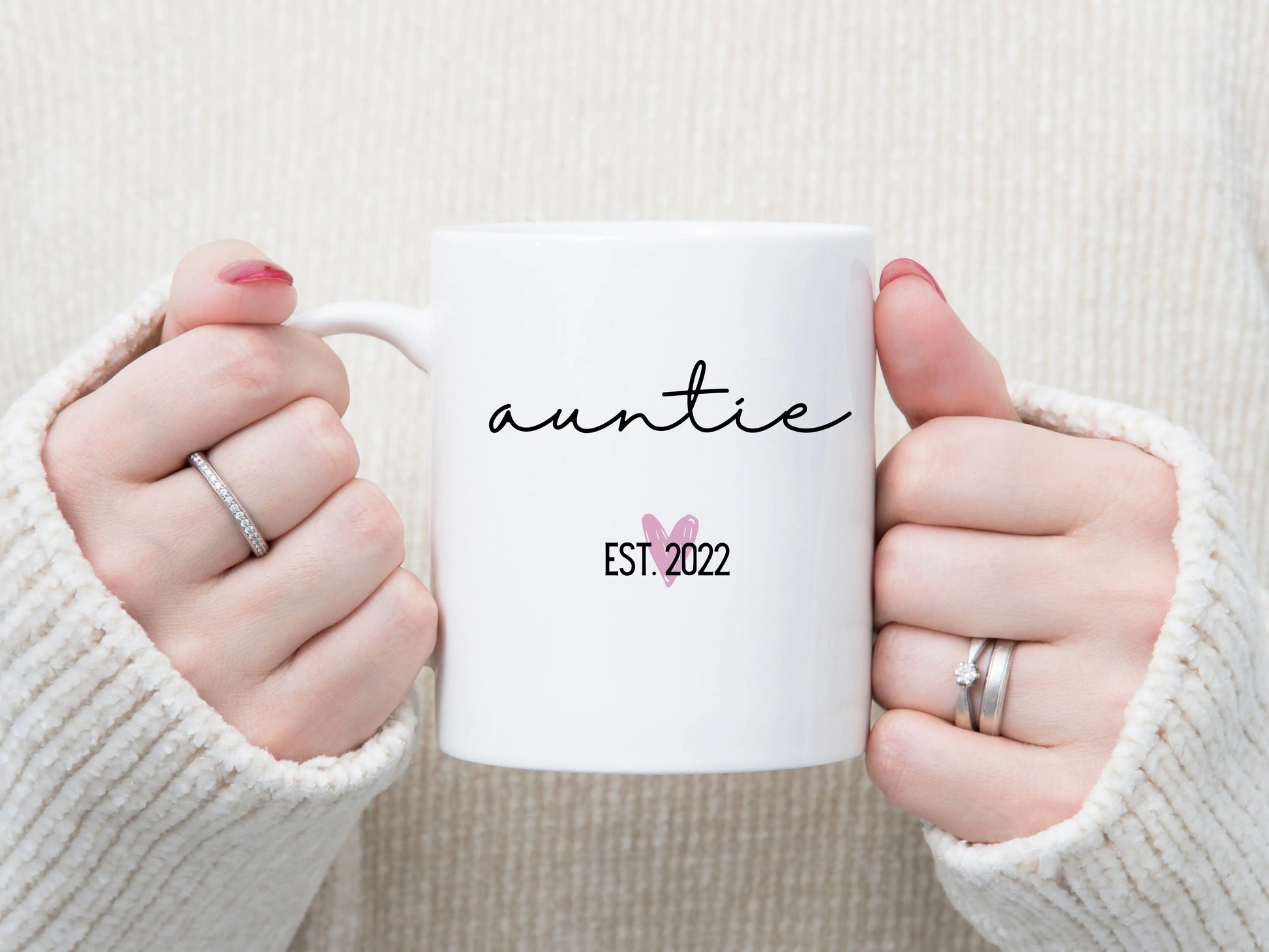 white handle coffee mug that says "Auntie" in a nice script font. there's a little pink heart below it with "EST. ___" for the year.