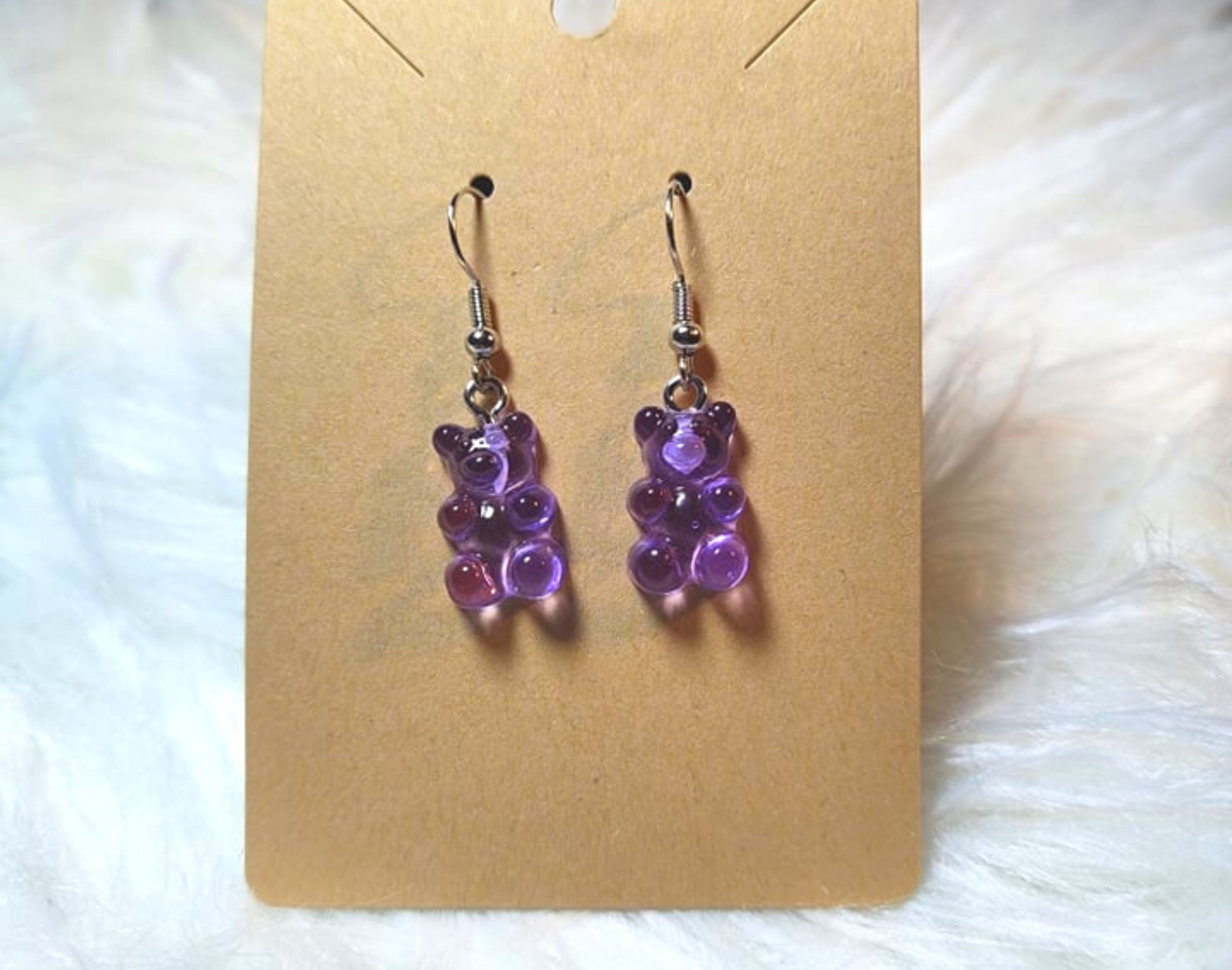 An earring card with dangle bear earrings. Silver metal components and the bears are a transparent purple color.