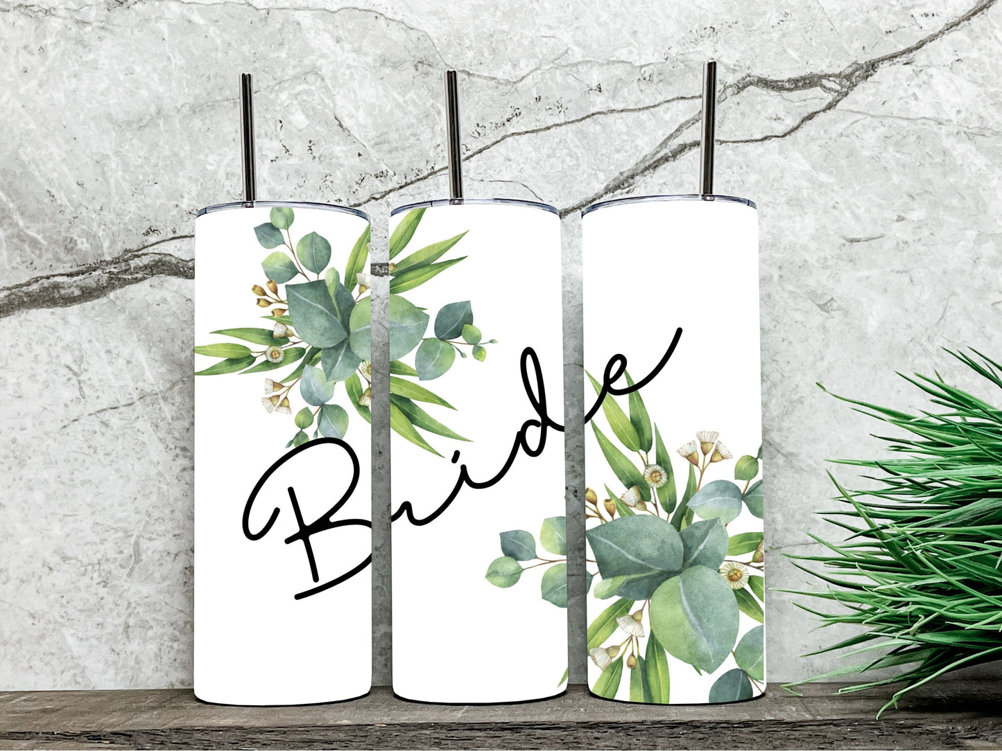 three views of the tumbler next to eachother. It is white in color with "Bride" in a nice script font with white florals and greenery. Very simple looking.