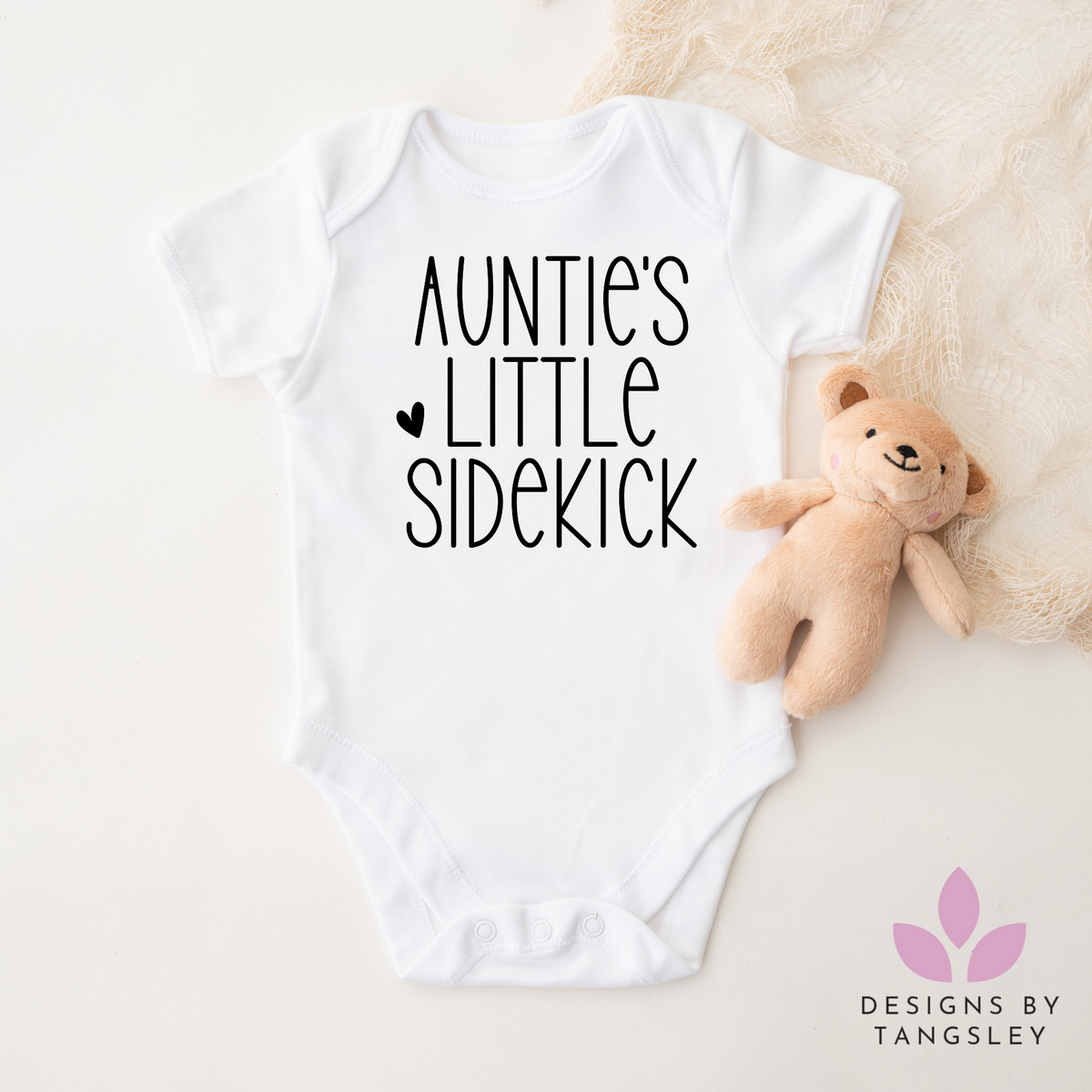 White shortsleeved bodysuit that says auntie's little sidekick with a cute heart in black.