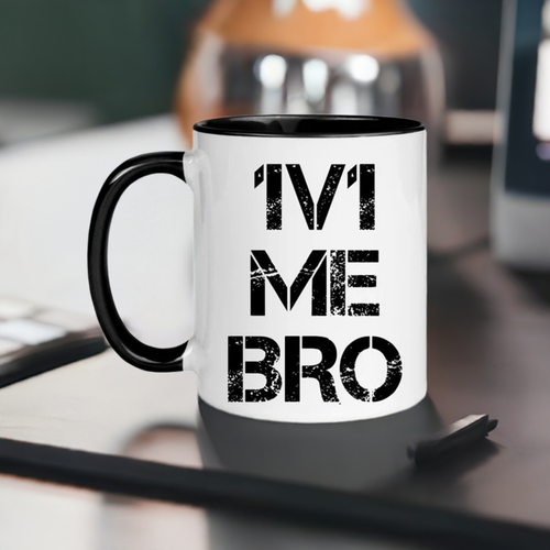 White coffee mug with black handle and black inside. It says "1v1 ME BRO" in a faded masculine font