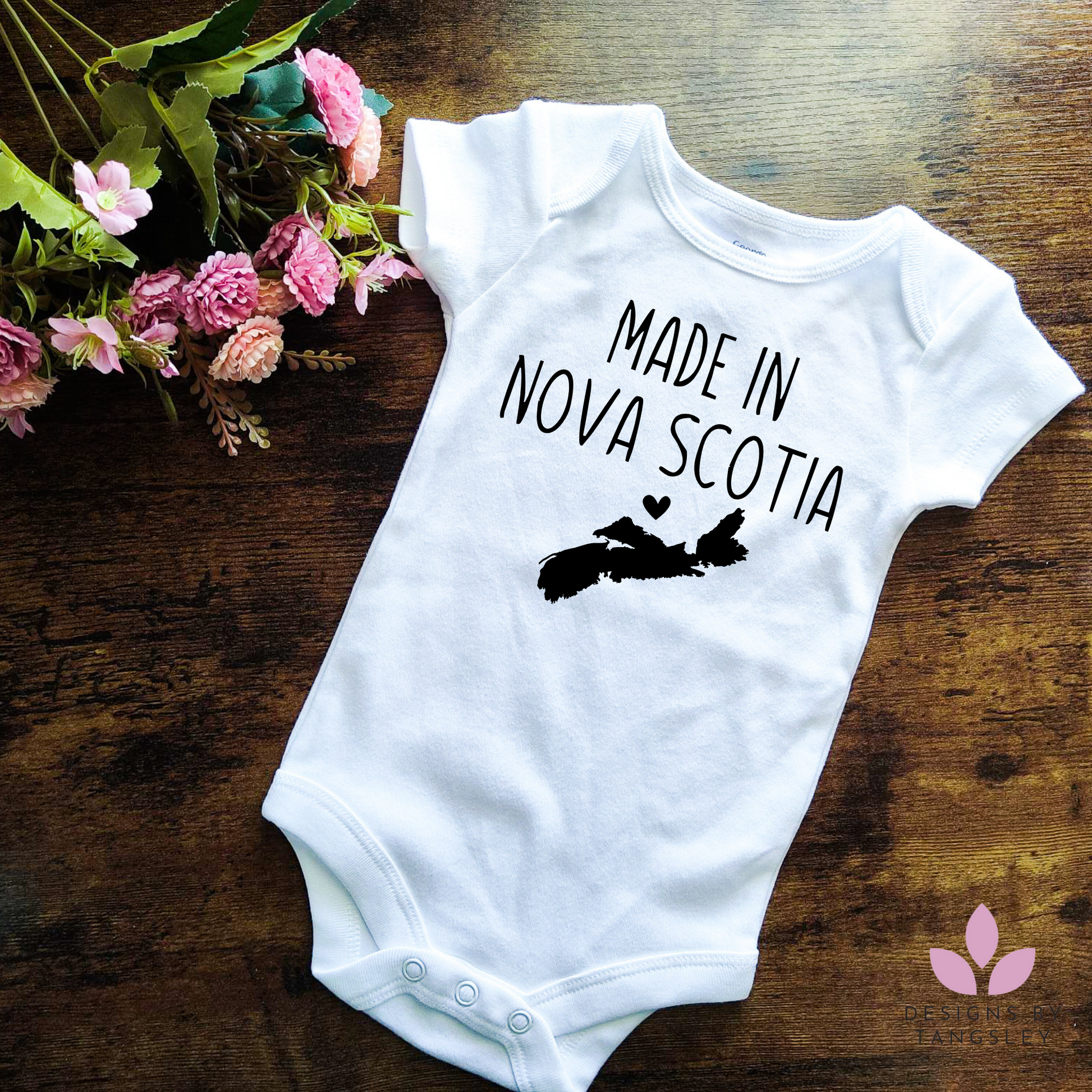 Shortsleeve white baby bodysuit with black design that says MADE IN NOVA SCOTIA with an image of NS on a map with a heart.