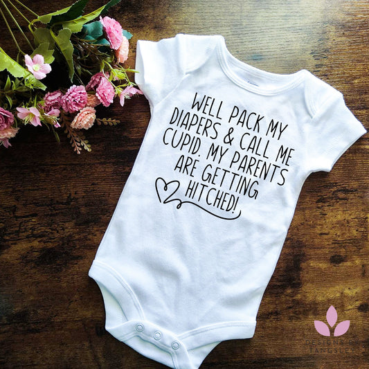 white baby bodysuit with black design. it says WELL PACK MY DIAPERS AND CALL ME CUPID. MY PARENTS ARE GETTING HITCHED! With a heart.