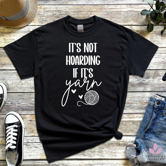 black t-shirt with "IT'S NOT HOARDING IF IT'S yarn" in white with a ball of yarn and two hearts 