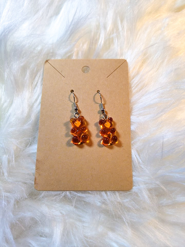 An earring card with dangle bear earrings. Silver metal components and the bears are a transparent orange color.