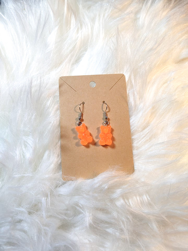 An earring card with dangle bear earrings. Silver metal components and the bears are orange in color.