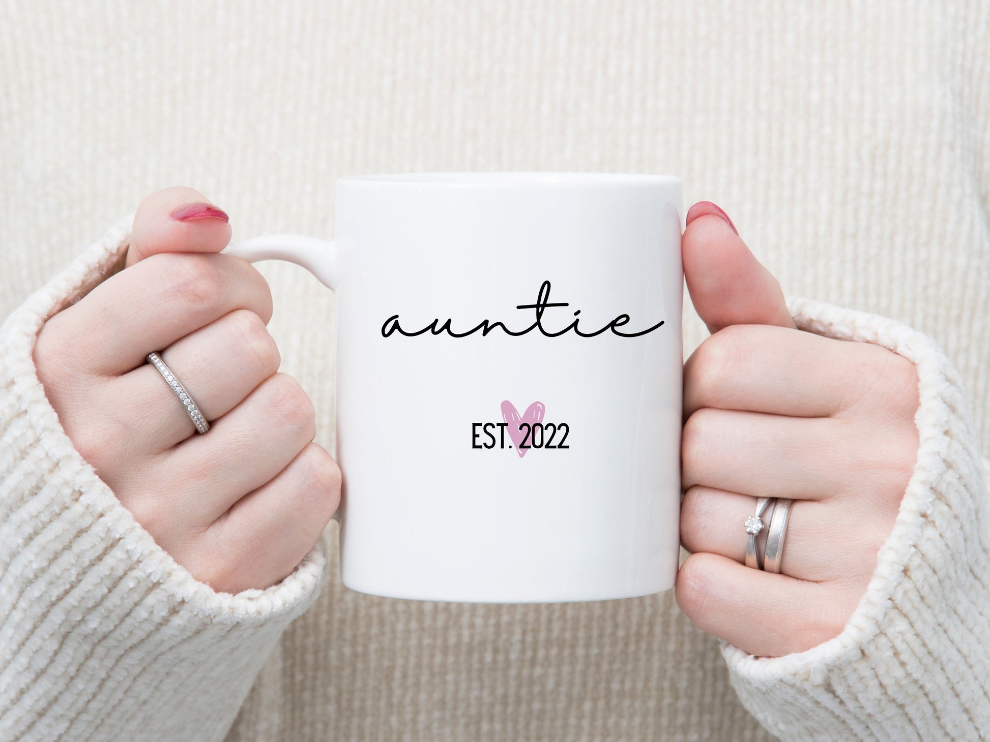 white handle coffee mug that says "Auntie" in a nice script font. there's a little pink heart below it with "EST. ___" for the year. 