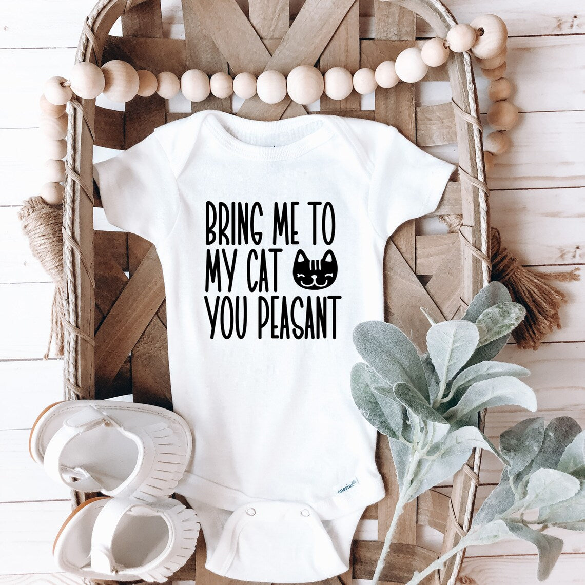 white bodysuit in a cute basket. it says "bring me to my cat you peasant" with an image of a smiling cat.