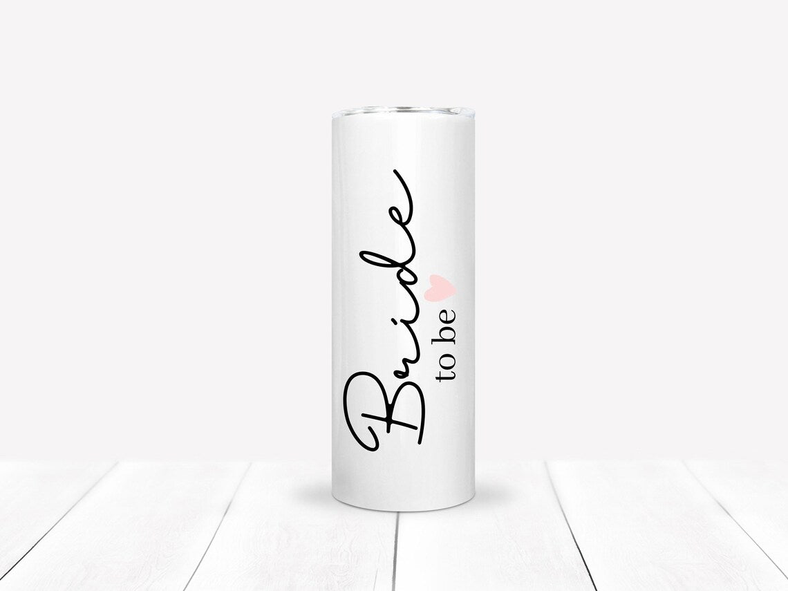 Simple white 20 oz skinny tumbler. It says Bride to be with a light pink heart.